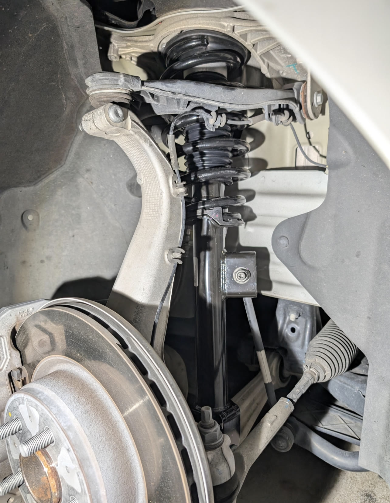 Genuine Tesla front spring and damper assembly installed in the wheel well of a pre-refresh car